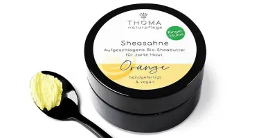 Runde, schwarze Dose mit weiß-gelber Aufschrift Sheasahne Orange, aufgeschlagene Bio-Sheabutter mit Ringelblumenoel, handgefertigt und vegan von der Naturseifen Manufaktur Uckermark.