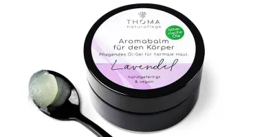 Runde, schwarze Dose mit weiß-lilafarbener Aufschrift Aromabalm Lavendel, pflegendes Oel-Gel mit ätherischem Lavendeloel für normale Haut, handgefertigt und vegan von der Naturseifen Manufaktur Uckermark.