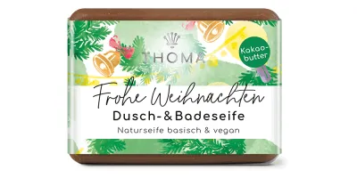 rechteckige, braune Seife mit weihnachtlicher Verpackung und Aufschrift Frohe Weihnachten, Dusch und Badeseife mit Kakaobutter von der Naturseifen Manufaktur Uckermark.