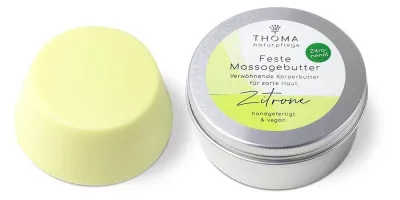 Runde, gelbe feste Massagebutter in Zitronenform neben silberner Dose mit weiß-gelber Aufschrift Zitronen Massagebutter, erfrischende und sinnliche Körperbutter mit Zitronenoel, handgefertigt und vegan von der Naturseifen Manufaktur Uckermark.